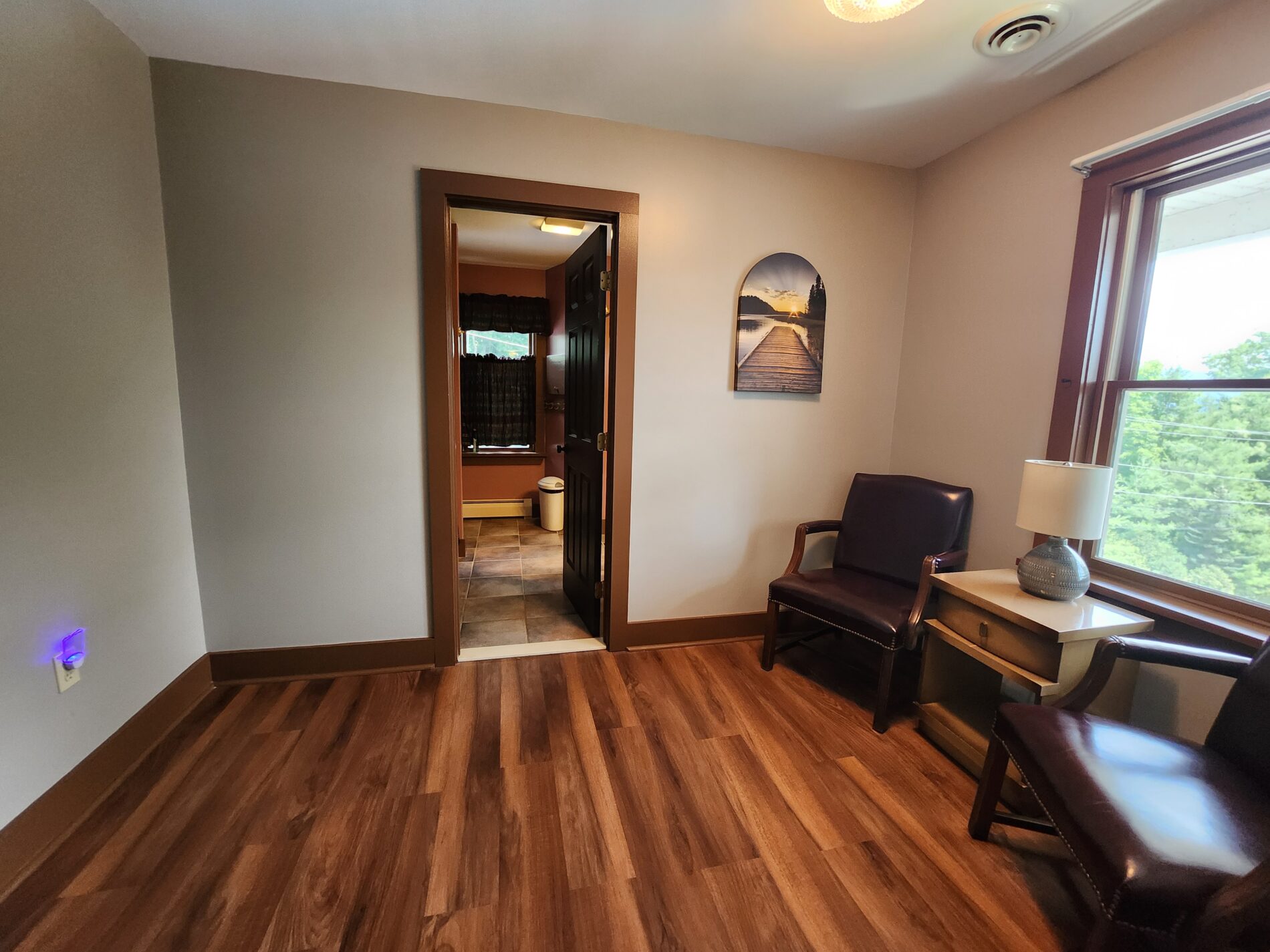 wooden floors with two leather chairs in front of window